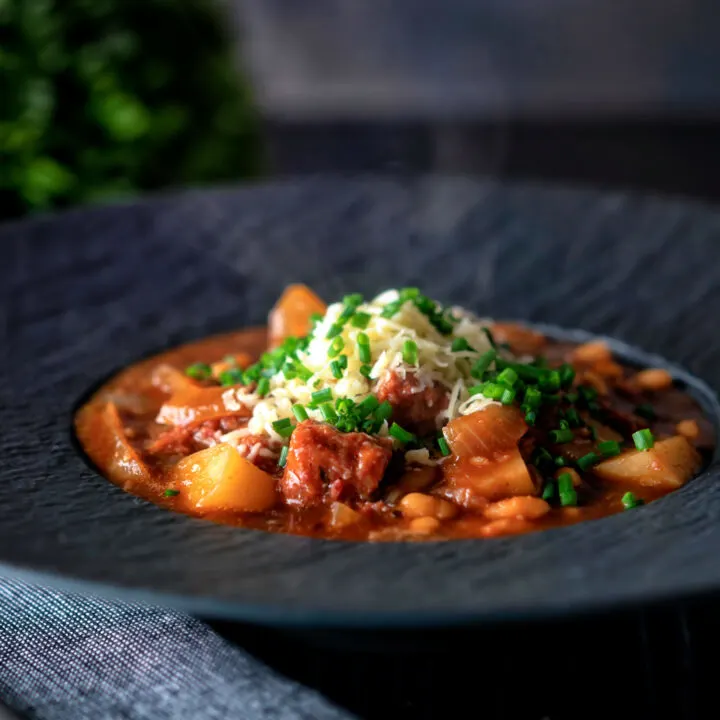 Canned corned beef stew with baked beans and potatoes topped with cheese and chives.