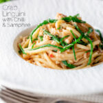 Crab linguini with chilli, lemon and samphire in a white bowl featuring a title overlay.