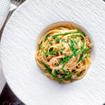 Overhead crab pasta with chilli, lemon and samphire in a white bowl featuring a title overlay.