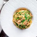 Overhead crab pasta with chilli, lemon and samphire in a white bowl featuring a title overlay.