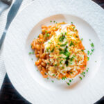 Overhead cheesy mashed potato topped fish finger and baked bean pie featuring a title overlay.