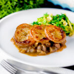 Traditional scalloped potato topped Lancashire hotpot with buttered cabbage on a plate.