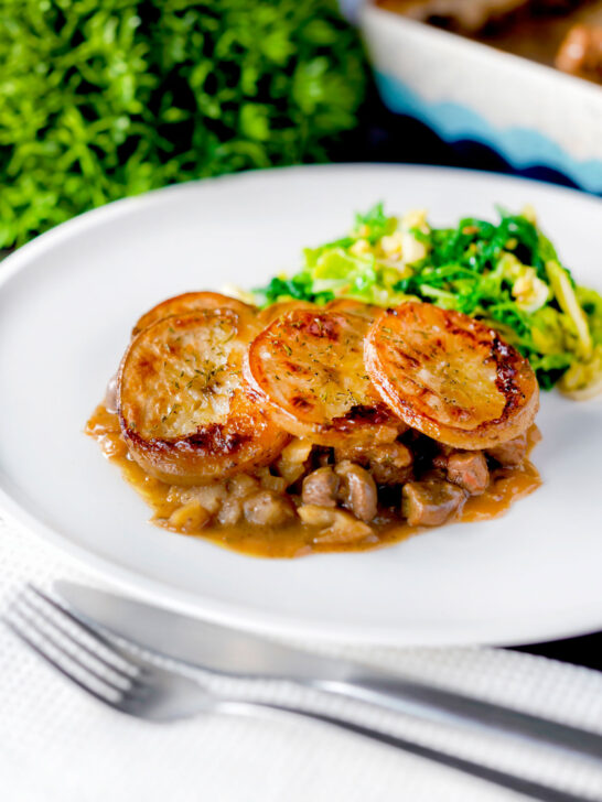 Traditional scalloped potato topped Lancashire hotpot with buttered cabbage on a plate.