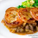 Close scalloped potato topped Lancashire hotpot with buttered cabbage on a plate featuring a title overlay.