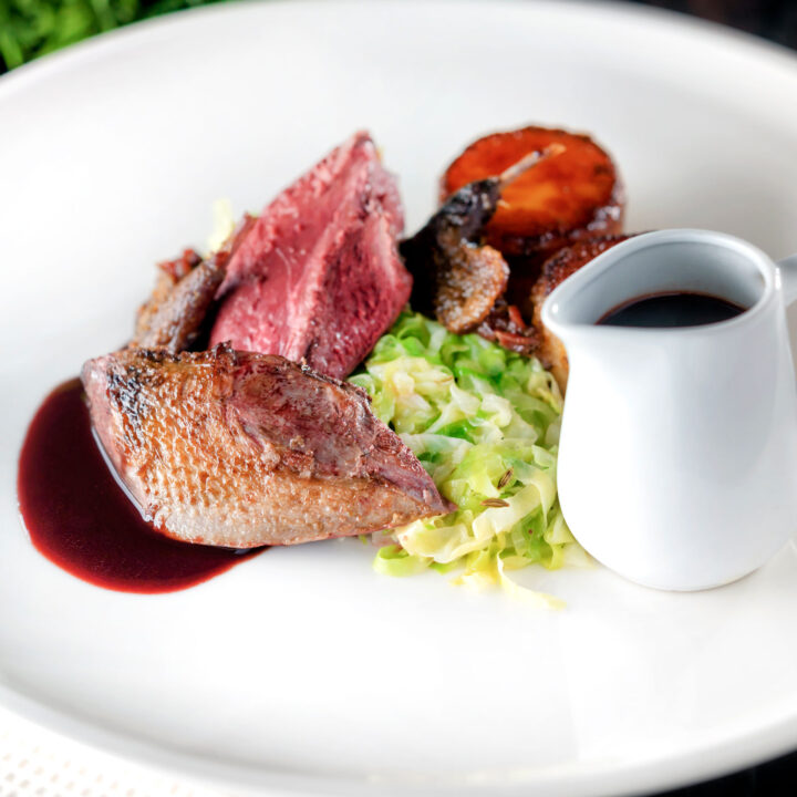 Pink roast pigeon breasts, confit legs, red wine sauce, buttered cabbage and fondant potatoes.