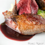 Close-up roast pigeon breasts, confit legs, red wine sauce, featuring a title overlay.