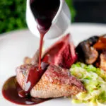 Red wine sauce poured over roast pigeon breast served with buttered cabbage.