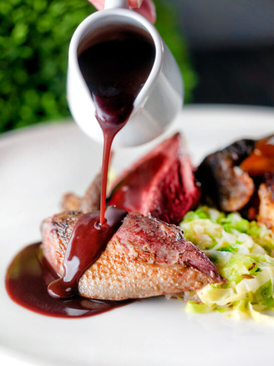 Red wine sauce poured over roast pigeon breast served with buttered cabbage.