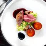 Overhead roast pigeon breasts, confit legs, red wine sauce, cabbage and fondant potatoes.