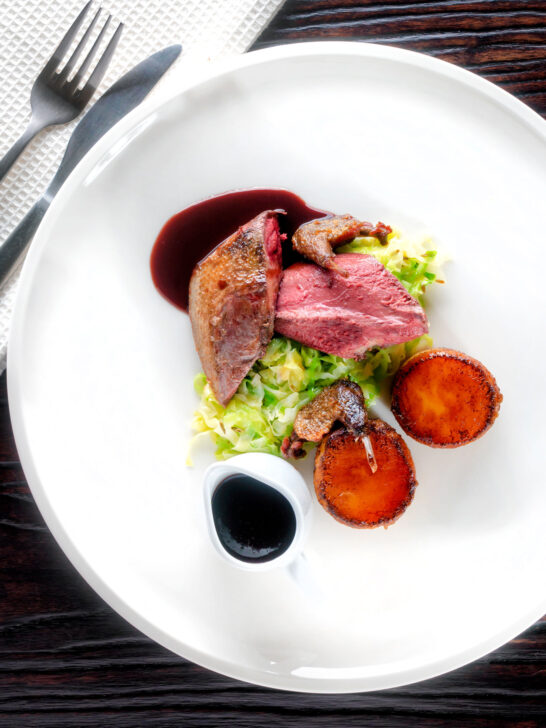 Overhead roast pigeon breasts, confit legs, red wine sauce, cabbage and fondant potatoes.