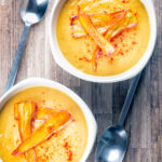 Overhead roasted curried parsnip soup with paprika and fried carrot crisps.