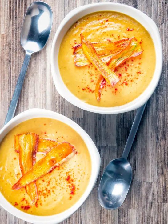 Overhead roasted curried parsnip soup with paprika and fried carrot crisps.