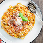 Overhead homemade spaghetti and meatballs with grated parmesan cheese.