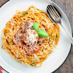 Overhead homemade spaghetti and meatballs with grated parmesan cheese featuring a title overlay.