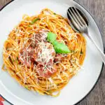 Overhead homemade spaghetti and meatballs with grated parmesan cheese featuring a title overlay.