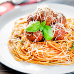 Homemade spaghetti and meatballs with grated parmesan cheese.