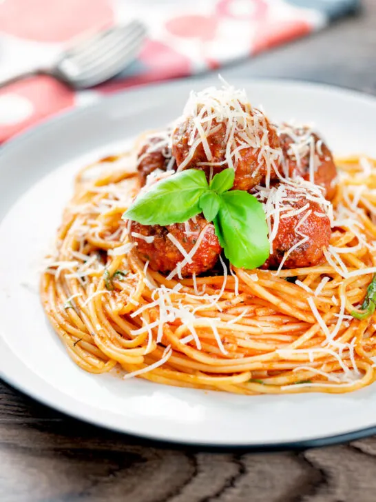 Homemade spaghetti and meatballs with grated parmesan cheese.