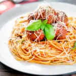 Homemade spaghetti and meatballs with grated parmesan cheese featuring a title overlay.