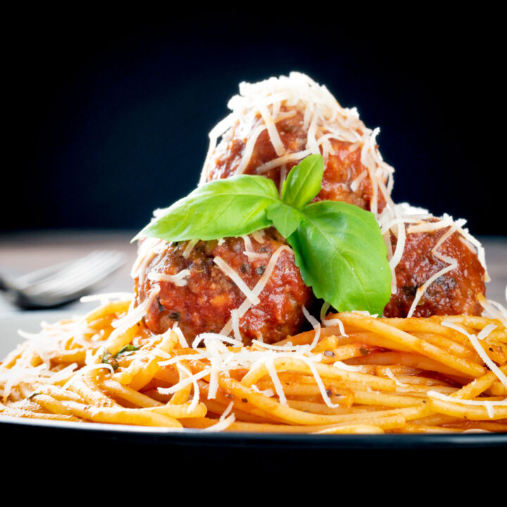 Homemade spaghetti and meatballs with fresh basil and grated parmesan cheese.