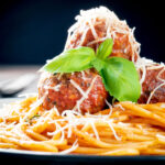 Homemade spaghetti and meatballs with grated parmesan cheese and basil.