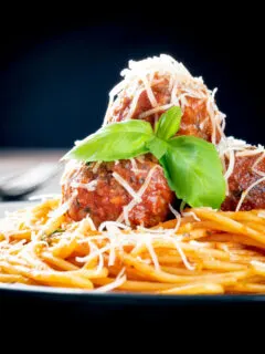 Homemade spaghetti and meatballs with grated parmesan cheese and basil.
