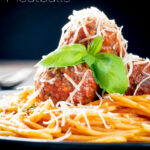 Homemade spaghetti and meatballs with grated parmesan cheese and basil featuring a title overlay.