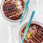 Overhead spicy pork ramen soup with spring onions.