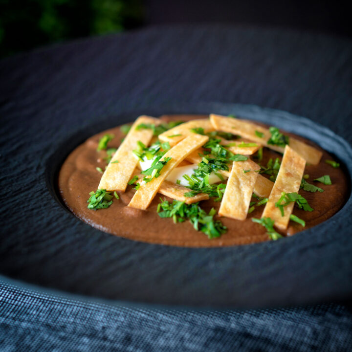 Spicy Mexican black bean soup topped with crispy tortillas, sour cream and fresh coriander.