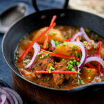 Pakistani aloo gosht meat and potato curry served with a naan bread.