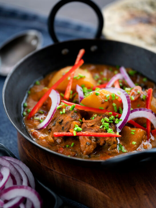 Pakistani aloo gosht meat and potato curry served with a naan bread.