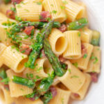 Close-up overhead bacon and asparagus pasta with mezzi rigatoni and fresh parsley.