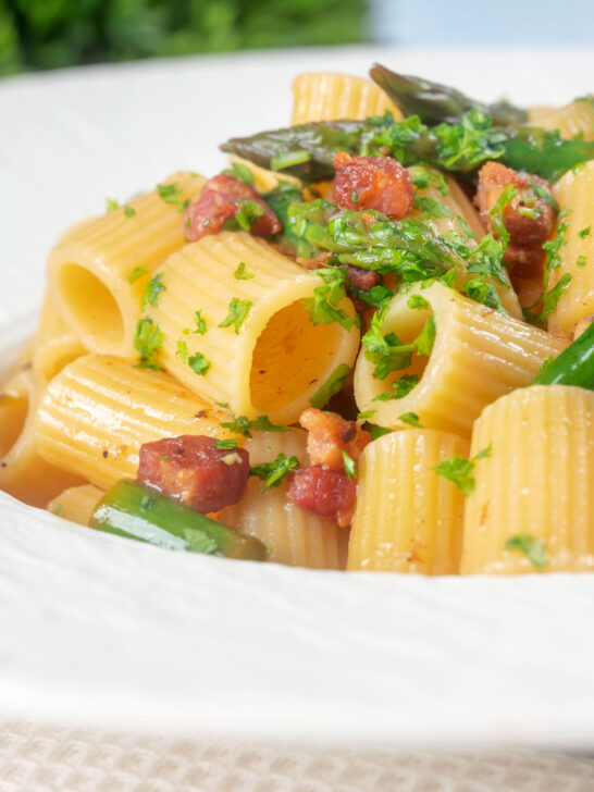 Close-up bacon and asparagus pasta with mezzi rigatoni and fresh parsley.