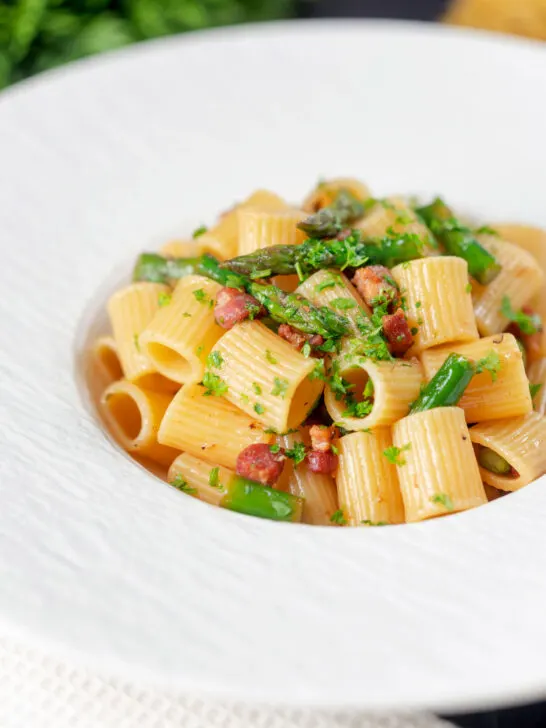 Bacon and asparagus pasta with mezzi rigatoni and fresh parsley.