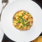 Overhead bacon and asparagus mezzi rigatoni and fresh parsley.