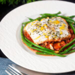 White fish baked in tomato sauce with green beans amandine.