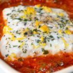 Close-up cod fish in a caper and tomato sauce.