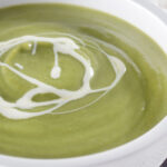 Close-up creamy broccoli and stilton soup with a swirl of cream.