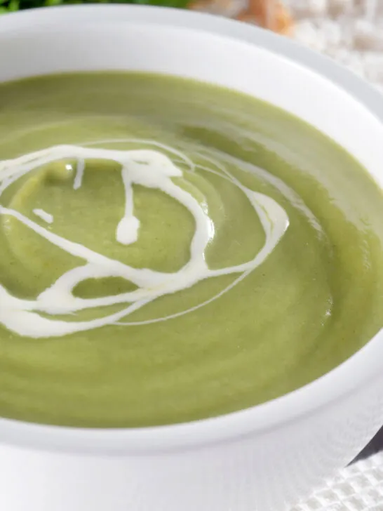 Close-up creamy broccoli and stilton soup with a swirl of cream.