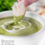 Crusty bread dipped into creamy broccoli and stilton soup featuring a title overlay.