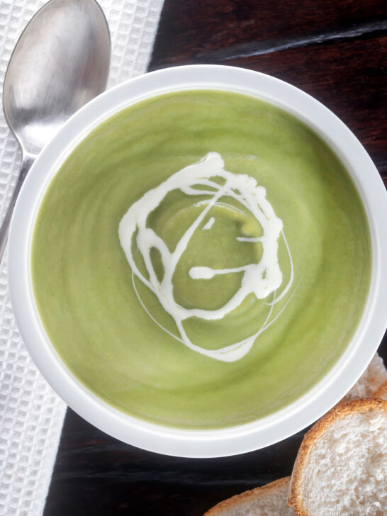 Overhead creamy broccoli and stilton soup with a swirl of cream.