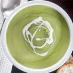 Overhead creamy broccoli and stilton soup with a swirl of cream featuring a title overlay.