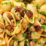 Close-up overhead chicken thigh and chorizo sausage pasta.