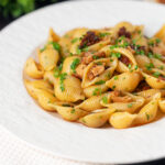 Chicken thigh and chorizo sausage pasta served with garlic bread featuring a title overlay.