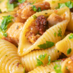 Close-up chicken thigh and chorizo sausage pasta.