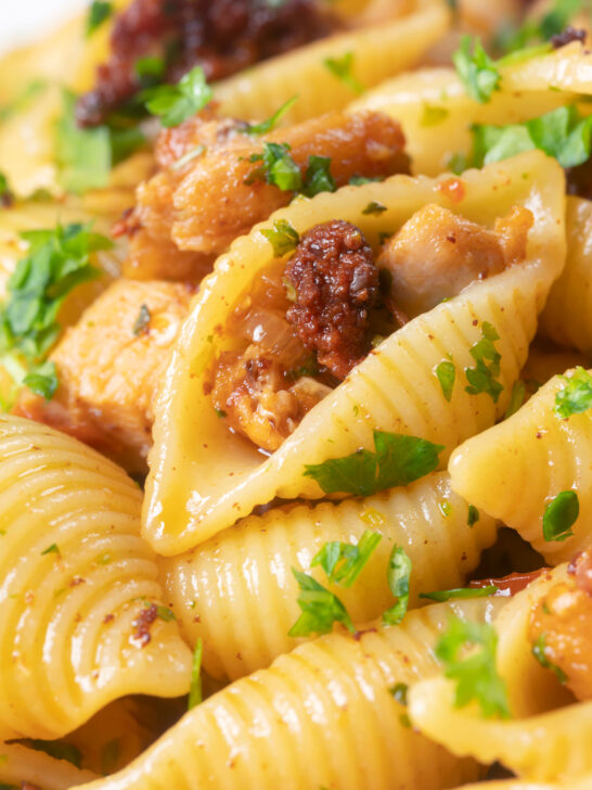 Close-up chicken thigh and chorizo sausage pasta.