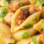 Close-up chicken thigh and chorizo sausage pasta featuring a title overlay.