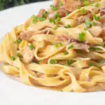 Close-up chicken and mushroom pasta with fresh chives.