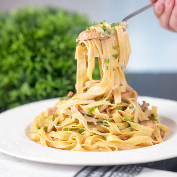 Chicken and mushrooom tagliatelle pasta being eaten with a fork.