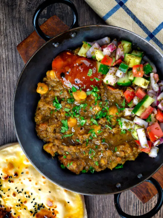 Overhead Indian-inspired chickpea and lentil curry with kachumber salad and mango chutney.