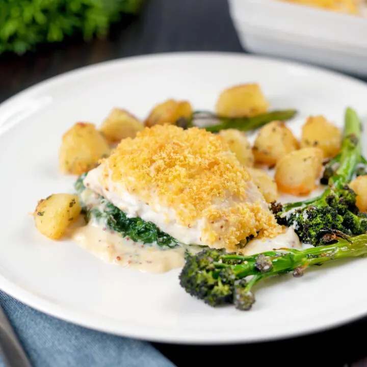 Baked cod Mornay with spinach and cheese sauce served with potatoes and broccoli.